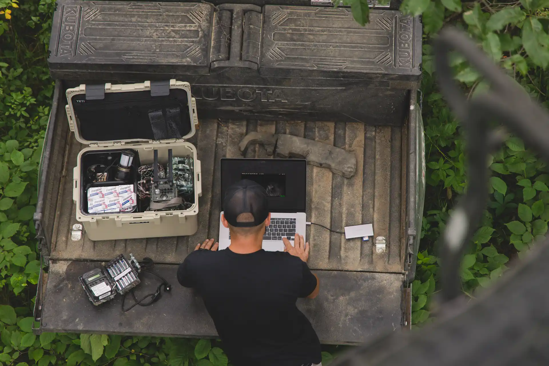 Man working in the back of a gator bed with a laptop